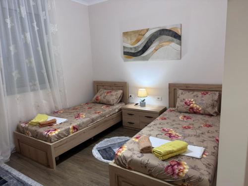a bedroom with two beds and a table with a lamp at Anika's Place in Korçë
