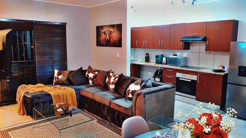 a living room with a couch and a kitchen at Malaika Luxurious Crib, Jackal Creek Golf Estate, Northriding in Roodepoort
