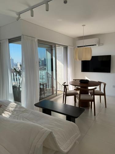 a bedroom with a bed and a table and a balcony at Departamento Premium en Puerto Norte con vista al río in Rosario