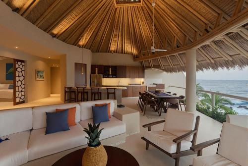 a living room with a couch and a kitchen and the ocean at Punta Majahua by PRC Hospitality in La Majahua