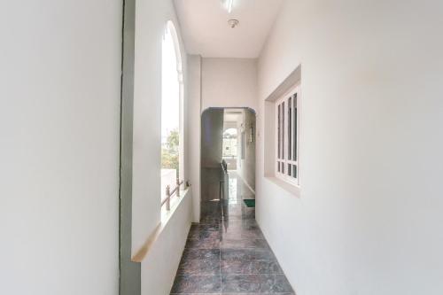 a hallway with a white wall and a window at Hotel O Vivekam Home Stay in Coimbatore