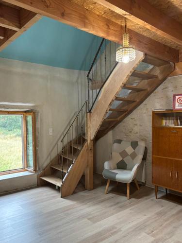 a living room with a staircase and a chair at Gîte au coeur de la forêt in Saint-Parize-le-Châtel