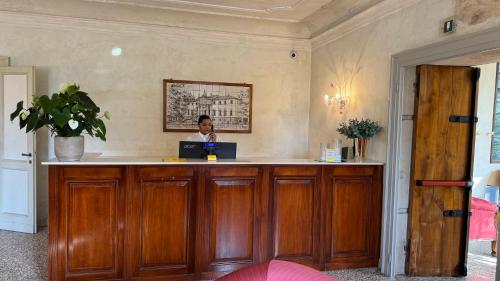 a woman sitting at a counter with a laptop at Hotel Villa Cornér Della Regina in Vedelago