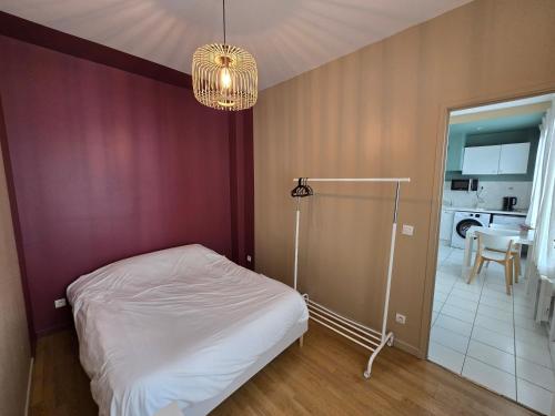 イシー・レ・ムリノーにあるAppartement spacieux 28m2 avec chambre séparéeの白いベッドとシャンデリアのある寝室