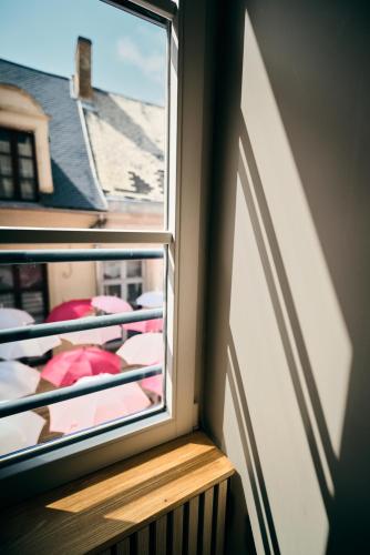 a window with a view of a balcony with umbrellas at La douce parenthèse in Laon