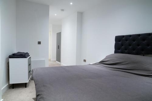a bedroom with a black bed and a white cabinet at Modern 2 Bed Penthouse with Stunning views in Manchester City Center in Manchester