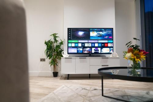 a television sitting on a white cabinet in a living room at Modern 2 Bed Penthouse with Stunning views in Manchester City Center in Manchester