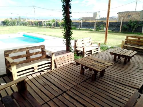 una terraza de madera con bancos y una piscina en Meraki, en Santa Lucía