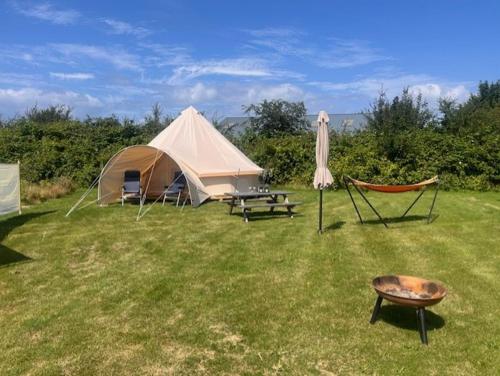 a tent and a chair and a table and a grill at Langø Fjordglamping Telt NR 4 in Nakskov