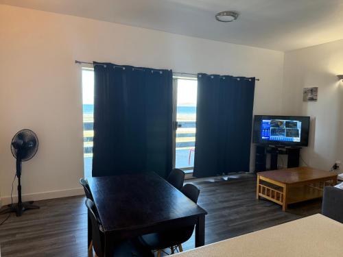 a living room with a table and a television at Sand Pebbles Inn in Qualicum Beach