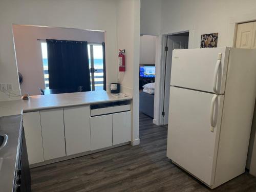 a kitchen with white cabinets and a white refrigerator at Sand Pebbles Inn in Qualicum Beach