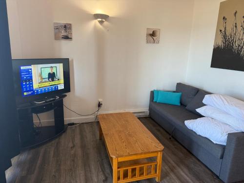 a living room with a couch and a tv at Sand Pebbles Inn in Qualicum Beach