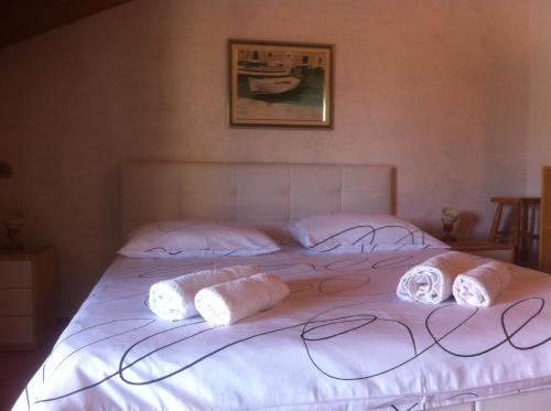 a large white bed with three pillows on it at Apartments Renato in Vrboska