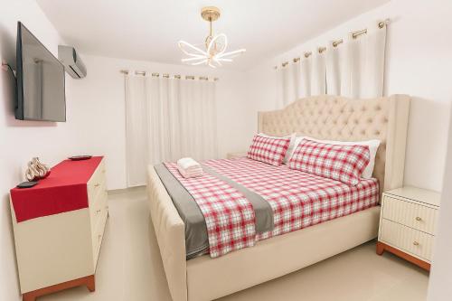 a white bedroom with a bed and a tv at Karamelo Tropical Getaway in Santiago de los Caballeros