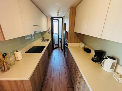 a kitchen with white cabinets and a wooden floor at Frente al Mar Concón - La Boca in Concón