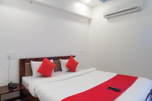 a bedroom with a bed with red and white pillows at Hotel O Shivam in Vadodara