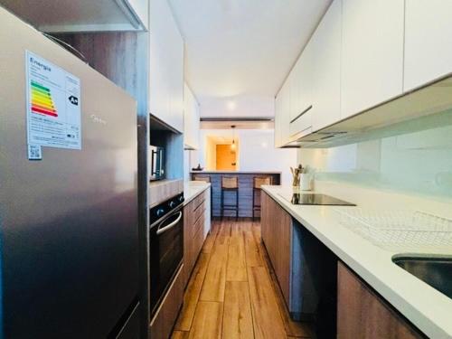 a kitchen with a stainless steel refrigerator and wooden floors at Frente al Mar Concón - La Boca in Concón