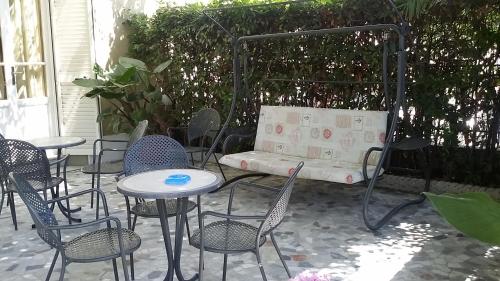 a patio with tables and chairs and a bench at Hotel Eros in Lido di Camaiore