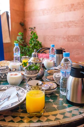 a table with plates and bottles of water and orange juice at Riad Mazouz102 Médina in Marrakech