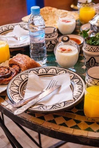 a table with plates of food and a bottle of water at Riad Mazouz102 Médina in Marrakech