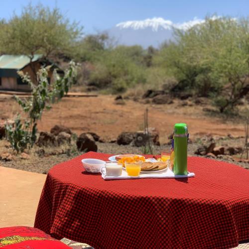 a red table with a plate of food and a green drink at Oldonyo Musa Amboseli Campsite in Rift Valley