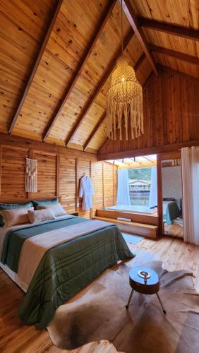 a bedroom with a large bed and a chandelier at Chale Vila dos Lagos in Venda Nova do Imigrante