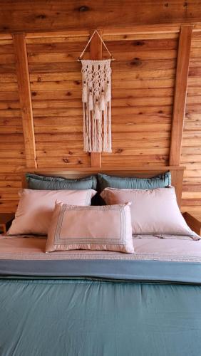 a bed in a room with wooden walls and pillows at Chale Vila dos Lagos in Venda Nova do Imigrante