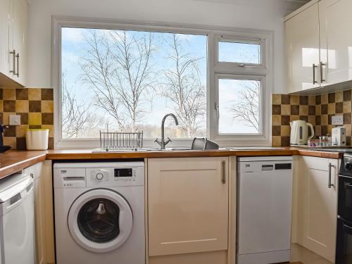 a kitchen with a washing machine and a window at Exmoor View in Blue Anchor