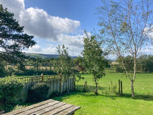 a wooden bench in a field with a fence at Exmoor View in Blue Anchor