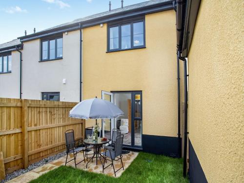 eine Terrasse mit Tisch, Stühlen und Sonnenschirm in der Unterkunft Wagtails in Dartmouth