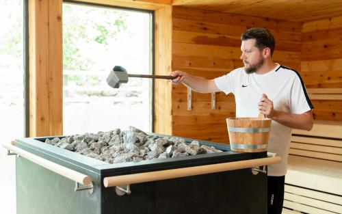 a man holding a spatula over a charcoal grill at MICHELS Wellness- & Wohlfühlhotel in Schalkenmehren