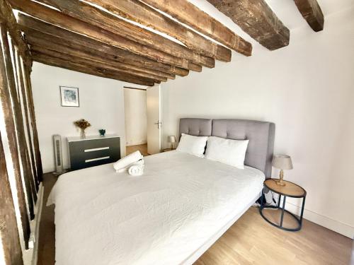 a bedroom with a large white bed with wooden ceilings at 80 m2-Heart of Le Marais -Sleeps 6 in Paris