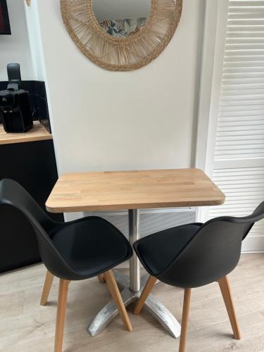 a table with two black chairs and a mirror at Rouzic - Studio Appart Hôtel in Lannion
