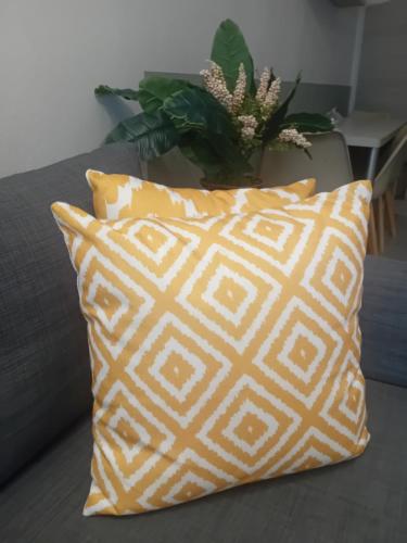 a yellow and white pillow sitting on a couch at Christi Iuxury Apartment in Preveza