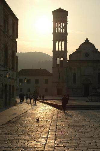 a group of people walking down a street with a clock tower at Old Town Hvar Rooms & Apartments in Hvar