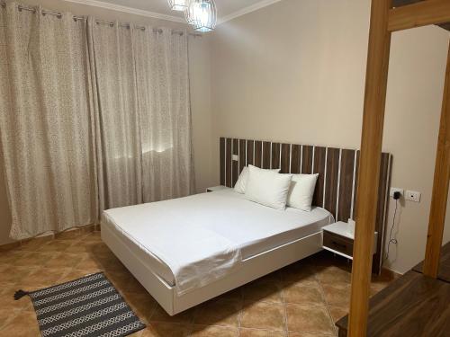 Un dormitorio con una cama con sábanas blancas y almohadas blancas. en Palm Suites Apartments, en Vlorë