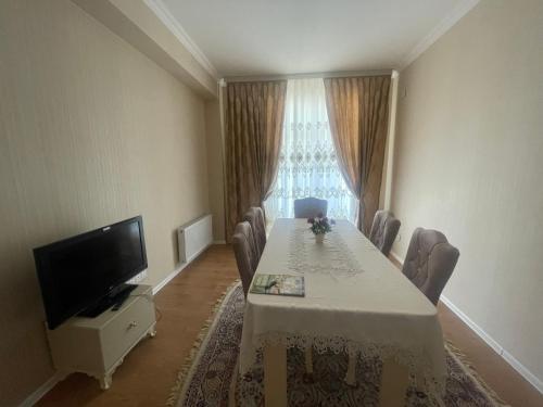 a dining room with a table with chairs and a television at Backpackers Base in Ganja