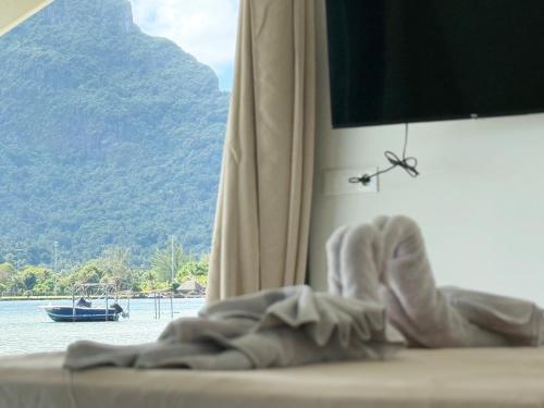 a bed with a view of the water and a boat at Lagoon house between sea and mountain, near Vaitape and Matira in Bora Bora