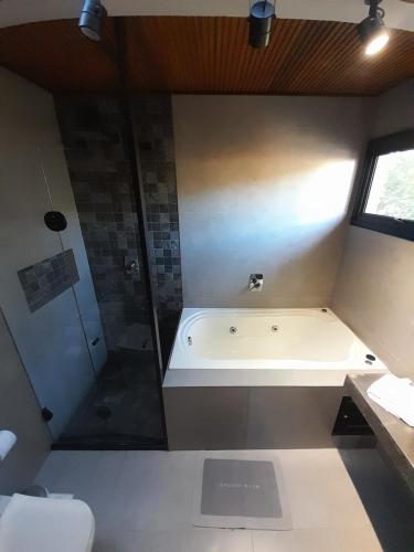 a bathroom with a bath tub and a shower at Pousada Kirana in Praia do Rosa
