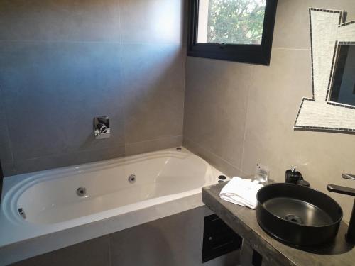 a bathroom with a bath tub and a sink at Pousada Kirana in Praia do Rosa