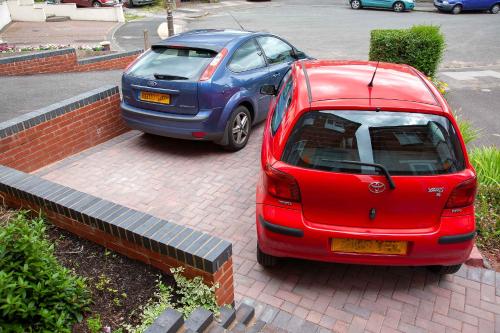 ein rotes und ein blaues Auto auf einem Parkplatz geparkt in der Unterkunft Comfortable Home near NEC, BHX in Birmingham