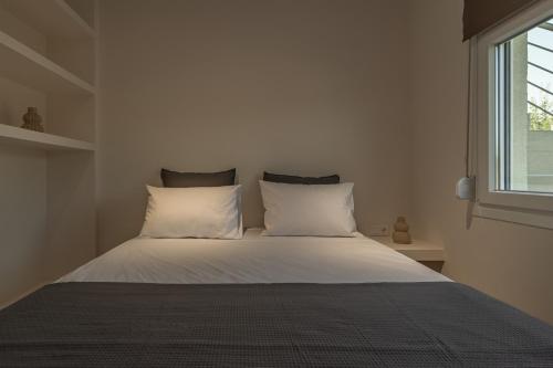 a bedroom with a bed with white sheets and a window at Elonea Villas, Luxury Villas and Studios in Kallikrateia Halkidiki with Garden, Veranda & BBQ in Nea Kalikratia