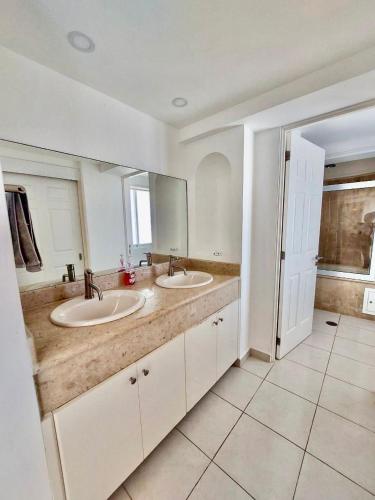 a bathroom with two sinks and a large mirror at FRENTE AL MAR A PIE DE PLAYA ALBERCA y JACUZZI in Mazatlán
