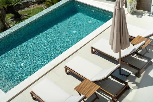 an image of a swimming pool with two chairs and an umbrella at Madeira Protea Retreat- Villa with Heated Private Pool, Gym and Office in Campanário