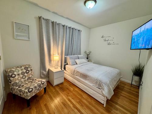 a bedroom with a bed and a chair and a tv at Private 1st floor Apartment - Only 5 min Away from Newark Airport and 30 min to NYC in Elizabeth