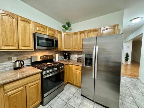a kitchen with wooden cabinets and a stainless steel refrigerator at Private 1st floor Apartment - Only 5 min Away from Newark Airport and 30 min to NYC in Elizabeth