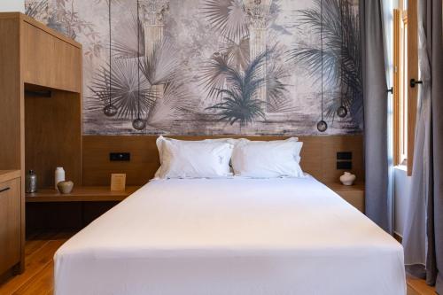 a bedroom with a large white bed with a wall at Ode Aristofanous - Urban Boutique Hotel in Athens