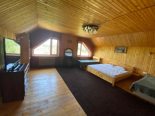 an attic room with two beds and a tv in it at Під Явором in Vorokhta