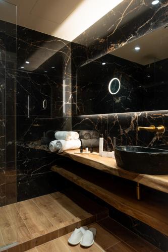 a black bathroom with a sink and a mirror at Ode Aristofanous - Urban Boutique Hotel in Athens