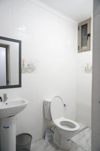 Un baño blanco con inodoro y lavabo. en Hôtel Nakhil Dak Hay Salam, en Dakhla